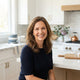 A diverse, smiling woman in a bright kitchen setting, representing a satisfied customer for a kitchen gadget store.